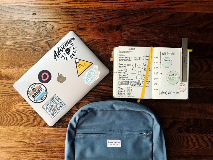 Schreibtisch mit Laptop, Rucksack und Notizbuch