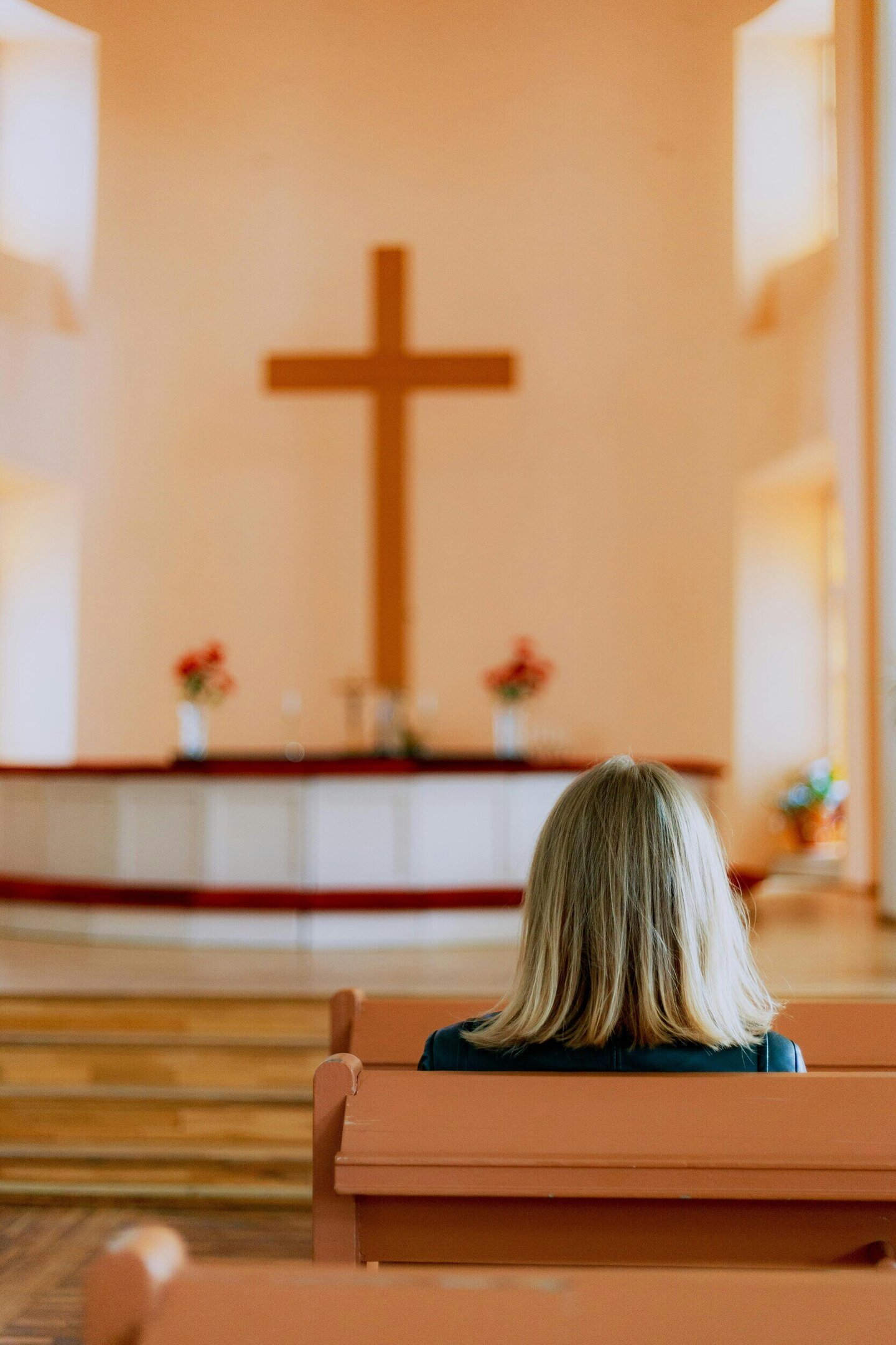 Frau sitzt in Kirche vor Altar