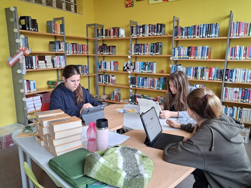 Schülerinnen arbeiten in der Bibliothek an ihren Projektpräsentationen